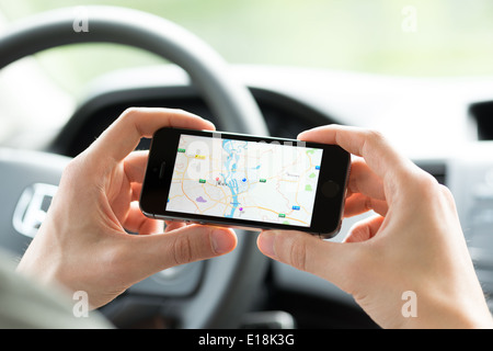 Man in the car planning a route using a Google Maps application on Apple iPhone 5S Stock Photo