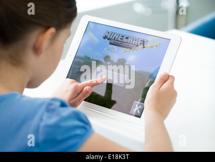 Little girl start playing Minecraft game on brand new Apple iPad Air. Minecraft is very popular game for mobile devices Stock Photo