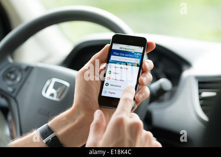 Man in a car planning a trip using Tripadvisor app on Apple iPhone 5S Stock Photo