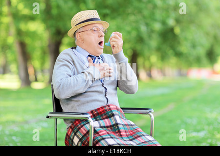 Senior man choking in park and holding an inhaler Stock Photo