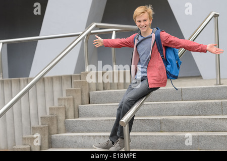 Playful teenage student sliding down railing on school stairway Stock Photo