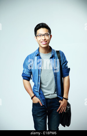 Young happy asian man standing on gray background Stock Photo