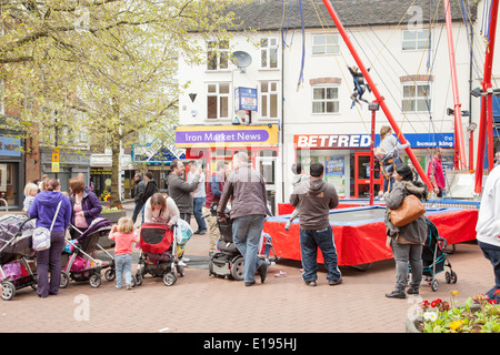 Parents enjoying watching their children, in Newcastle town centre playing on bungee swings, Newcastle under Lyme Staffordshire Stock Photo