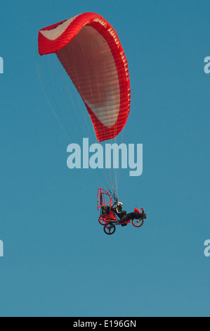 Paraglider flying over the clear blue sky Stock Photo