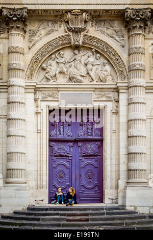 Two girls at the huge wooden doors to Saint Etienne du-Mont Church, Latin Quarter, Paris France Stock Photo