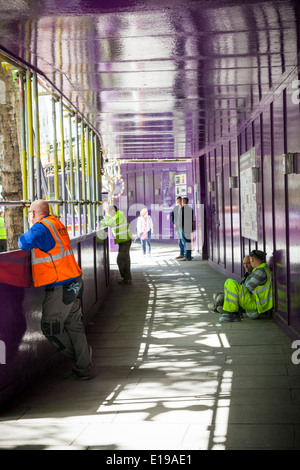 Builders taking a break in boarded safety path by construction site. Stock Photo