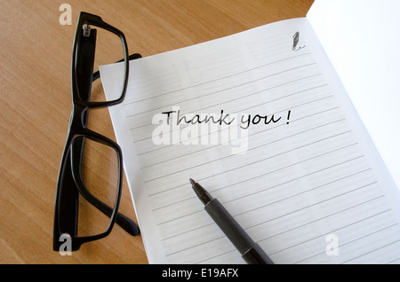 A thank you car with glasses on a wooden desk Writing a Thank You Note Stock Photo