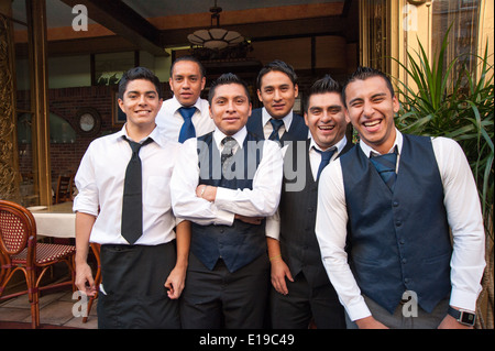 Group of Hispanic waiters posing for a photo outside restaurant on Mulberry Street in Little Italy, New York City, USA Stock Photo