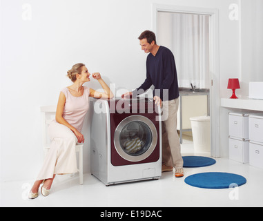 Housework, young woman and man doing laundry at home Stock Photo