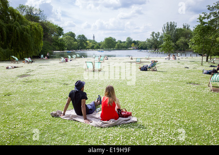Young couple sitting amongst the daisies in Regent's Park, London, England, UK Stock Photo
