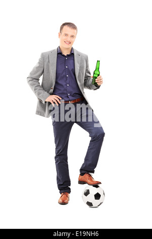 Young male football fan holding a beer and standing with a ball under his foot Stock Photo