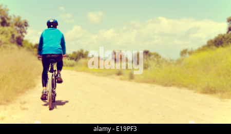 a young man riding a mountain bike on a dirt road Stock Photo