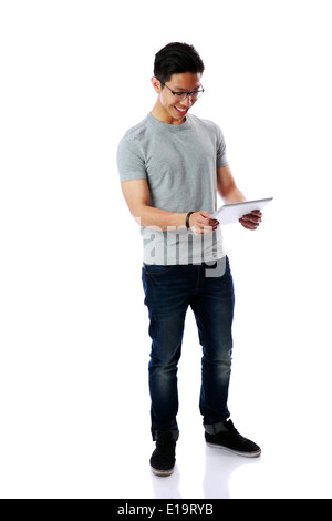 Full-length portrait of a young happy asian man standing with tablet computer over white background Stock Photo