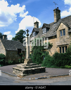 The medieval stone cross in the delightful cotswold village of Stanton on a summers day. Stock Photo