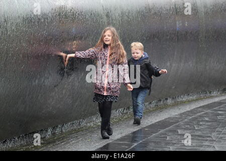 Sheffield, South Yorkshire, UK.  28 May 2014.  Heavy rain doesn’t deter youngsters from playing in Sheffield’s watery ‘Cutting Edge’ sculpture in Sheaf Square. © Deborah Vernon/Alamy Live News Stock Photo