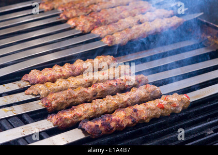 Cooking Adana kebabs on the restaurant style grill, smoke coming out from them that they might be ready Stock Photo