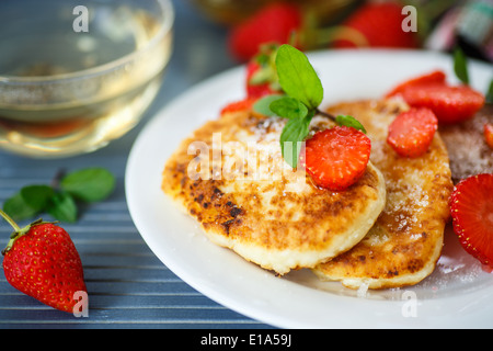 curd cheese pancakes fried with sugar and strawberries on a plate Stock Photo