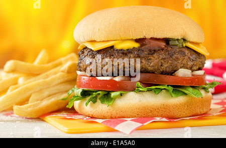 A classic style cheeseburger with beef, cheese, lettuce, tomatoe, onion, mustard, ketchup, and relish with french fries. Stock Photo