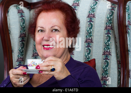 Senior woman having strong Turkish coffee and have a pleasant smile on her face Stock Photo