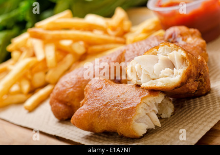 A delicious crispy battered deep fried fish and chips with greens and ketchup. Stock Photo
