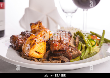 Mixed chicken, lamb adana shish kebabs served served on gyro doner with rice pilaf and garnished with green vegetables, Stock Photo