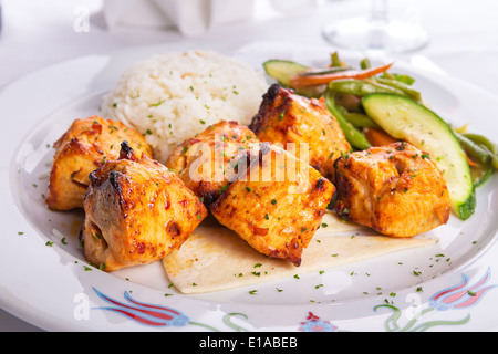 Zesty chicken shish kebabs served with rice pilaf on a tiny lavash bread garnished with cooked vegetables zucchini, green beans Stock Photo