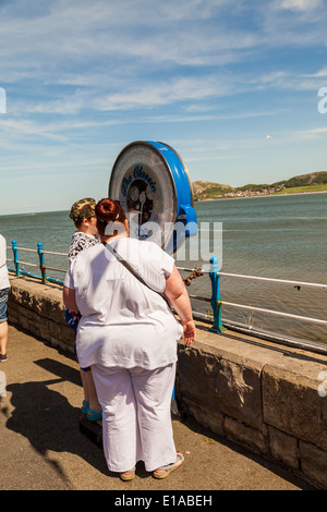 Over weight woman, standing at outdoor scales on Llandudno pier with a friend, Llandudno, Wales, United Kingdom. Stock Photo