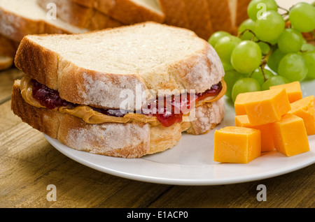 A nutritious peanut butter and jelly sandwich with cheddar cheese and grapes. Stock Photo