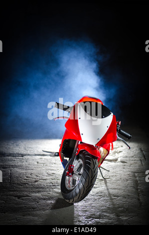 Photograph of a mini moto in a disused warehouse with a black background. Stock Photo