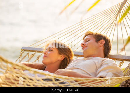 Romantic couple relaxing in tropical hammock at sunset Stock Photo
