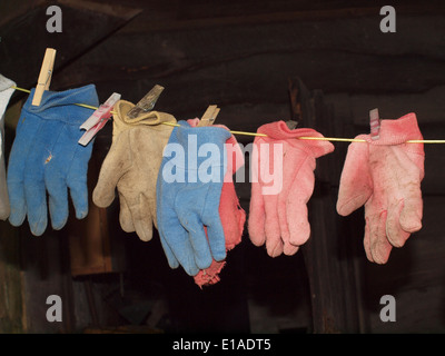 many red blue and white well-used gardening gloves hanging on a line to dry Stock Photo
