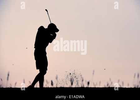 Silhouette of golf player taking a shot at sunset Stock Photo