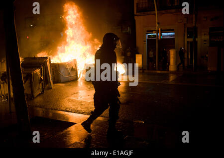 Barcelona, Spain, 28th May, 2014.  An antiriot police officer passes  in front of a burning barricade in the streets of Barcelona. Second night of protests and riots in the Sants neighborhood of Barcelona after the eviction of a squat by the police. Credit:   Jordi Boixareu/Alamy Live News