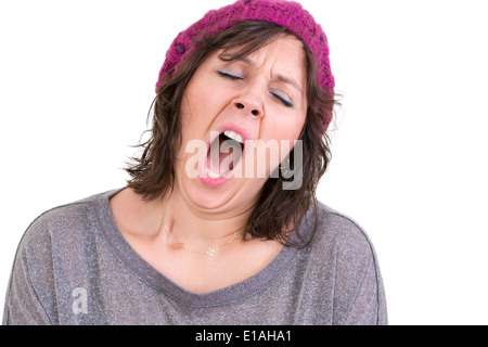 Exhausted or bored woman wearing a knitted beanie yawning with her mouth wide open and eyes shut isolated on white Stock Photo