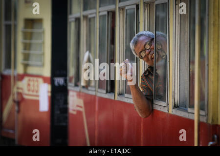 (140529) -- HIMACHAL PRADESH, May 29, 2013 (Xinhua) -- A passenger waves in a train on the Kalka-Shimla Railway in north India's Himachal Pradesh, May 28, 2014. The Kalka-Shimla Railway is a 762?mm narrow gauge railway in North-West India's Himachal Pradesh travelling along a mostly mountainous route from Kalka to Shimla. It is known for dramatic views of the hills and surrounding villages. The 96-km long railway was built since 1898 to provide a service to the highland town of Shimla. Three still fully operational railways, the Darjeeling Himalayan Railway in India's West Bengal, the Nilgiri Stock Photo