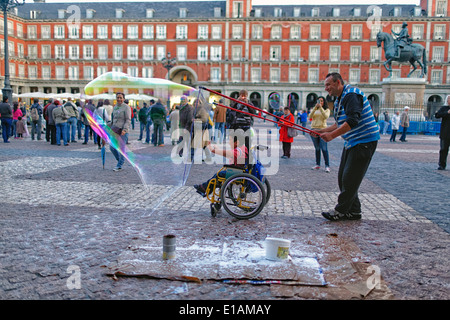 Soap Bubble Artist Enveloping Handicapped Child in a Wheelchair with Soap Bubble, Plaza Mayor, Madrid, Spain Stock Photo