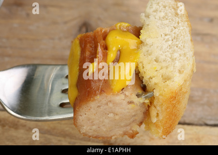 piece of hot pork sausage on a fork with mustard Stock Photo
