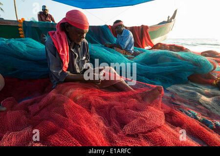 Fishermen repairing fishing nets on the beach, Varkala, Kerala, India Stock Photo