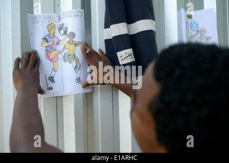 Street child, adolescent, attaching a self-painted picture of football players on a fence, supported by social workers, Central Stock Photo