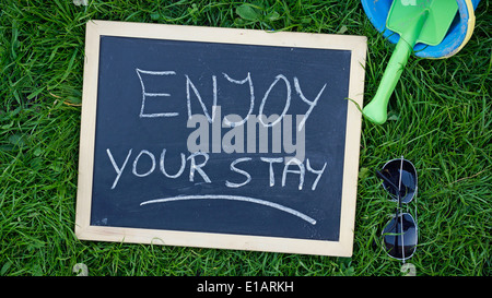 Enjoy your stay written on a chalkboard at the beach Stock Photo - Alamy