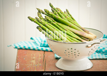 green asparagus in colander on old wooden background Stock Photo