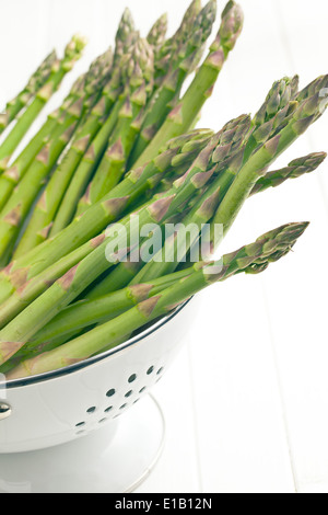 green asparagus in colander on white background Stock Photo