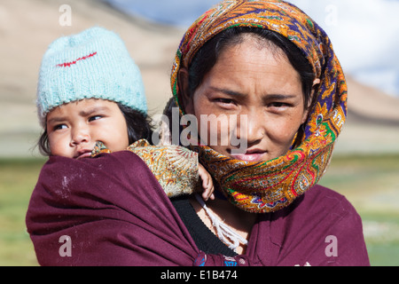 Woman in colorful patterned headscarf carrying child in a baby sling, region of Tso Kar, Rupshu, Changtang, Ladakh, India Stock Photo