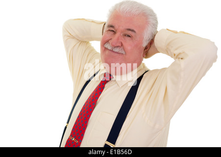 Smiling senior businessman relaxing with his hands behind his head in a red tie and braces, isolated on white Stock Photo