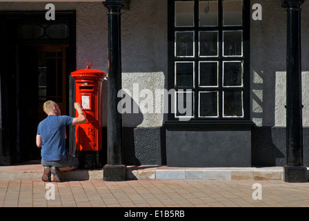 Young man painting pillar box red, Kendal, Cumbria, England UK Stock Photo
