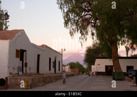 Girl riding bike in Plaza de Armas, Licancabur Volcano (19,455 ft.) in background, San Pedro de Atacama, Chile Stock Photo