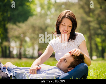 Young man is resting on woman's knees while she is caressing his hair Stock Photo