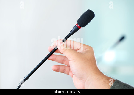 Close up of a hand holding a business conference microphone in a meeting room Stock Photo
