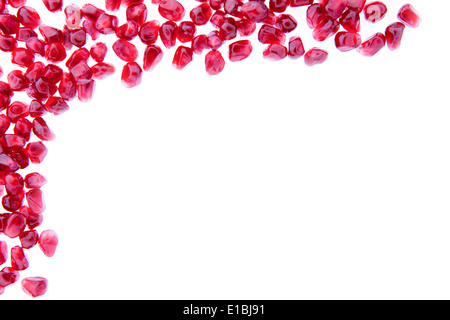 Border of fresh ripe pomegranate seeds arranged in the top left corner and isolated over a white background with copyspace Stock Photo