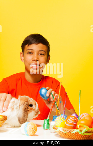 Boy with Easter eggs and cute rabbit on table Stock Photo
